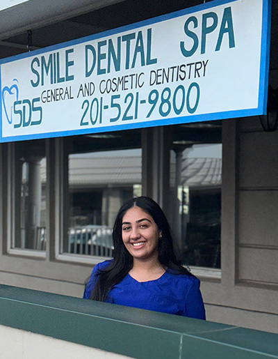 The image shows a person standing in front of a sign for a dental spa, with the text  SMILE DENTAL SPA  prominently displayed.