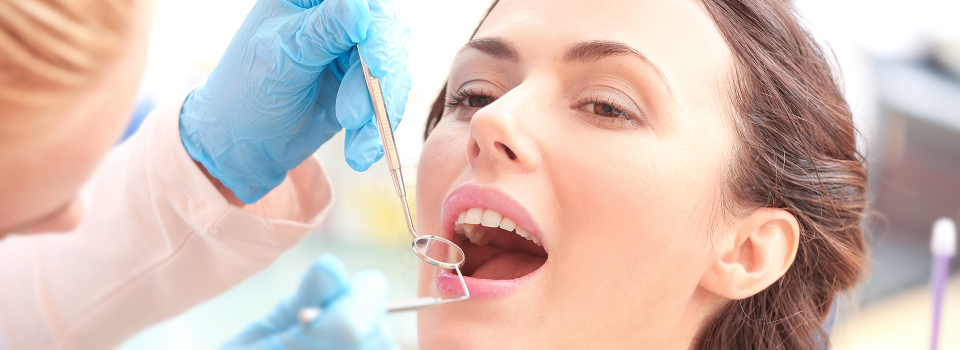 A dental hygienist performing a teeth cleaning procedure, using specialized tools on a patient s mouth.